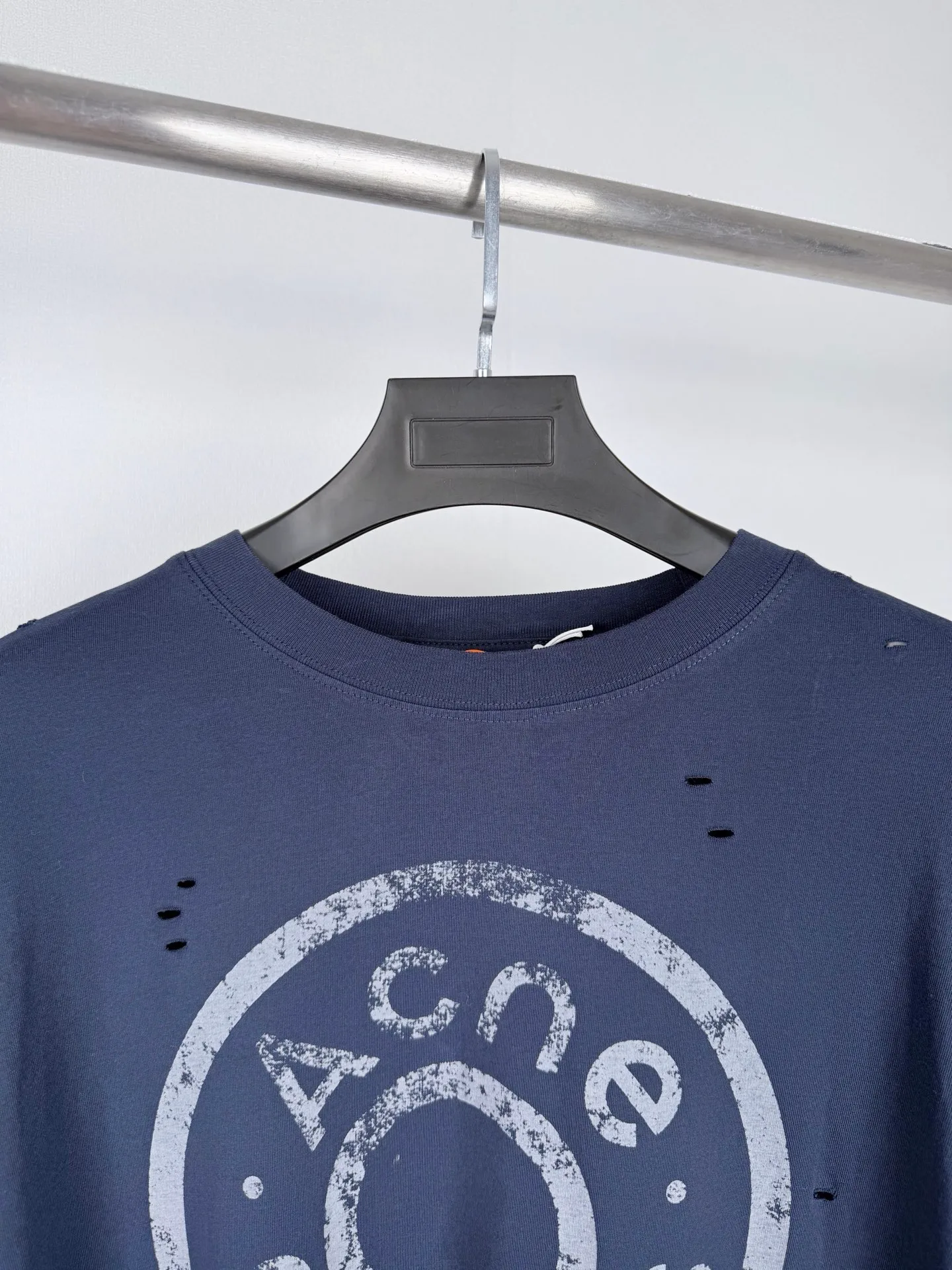 Acne Studios fake two-piece long-sleeved T-shirt with distressed logo. Customized Arashi weft-order plain cotton. Delicate and soft, warm and skin-friendly. Indigo-green covering the body. Matt low-saturation tones. Spreading the unique cool and relaxed charm of Retro deconstruction. The neat round neck is simple and restrained. The layered structure skillfully creates fake two-piece layers. The three-dimensional look of short sleeves stacked on long sleeves is naturally revealed in silence. The chest is embellished with the seasonal denim-style rivet logo. The Retro imprint is dimly deposited on the fabric. The body is staggered with frayed holes and stretches casually. The original texture of the deconstructed fabric. The loose shoulder silhouette is relaxed and relaxed. The cool and deconstructed Nordic aesthetics are integrated into daily clothing. The avant-garde quiet luxury style of alienation and restraint is demonstrated. Process 1: Using glue printing. The chest printing has been revised three times with the film screen. Use glue liquid paint to print the pattern on the fabric. Bake the fabric to fix the printing pattern. Process 2: Many parts of the body of the garment are worn by pure artificial regular positioning and manual brushing to add texture and depth to the surface of the garment to imitate the texture of natural wear and tear. Process 3: The fabrics are fermented and washed to give a better hand feel. Not easy to deform, not easy to shrink, not easy to fade, and maintain long-term beauty. Accessories: Customized 1:1 Acne trademark. Fit: Loose fit. Size: S M L XL